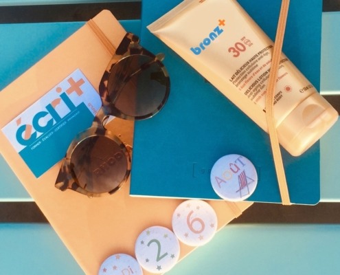 image montrant des carnets, des lunettes de soleil, de la crème solaire "bronz+", le tout aux couleurs d'écri+ : bleu et orange.